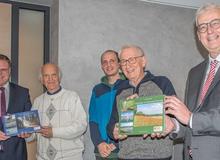 Die Landräte von Vechta und Diepholz halten mit den Autoren und einem Naturpark-Mitarbeiter die neuen Bücher in die Kamera