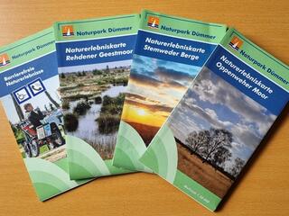 Vier Faltkarten fächerartig liegen auf einem Tisch.