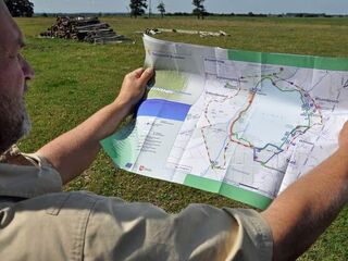 Ein Mann hält eine Naturerlebniskarte vor sich, auf der Wege und Stationen eingezeichnet sind.