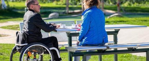 Rollstuhlfahrer und Frau an barrierefreien Picknicktisch