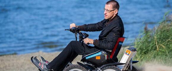 Rollstuhlfahrer mit Geländerollstuhl Zoom am Strand