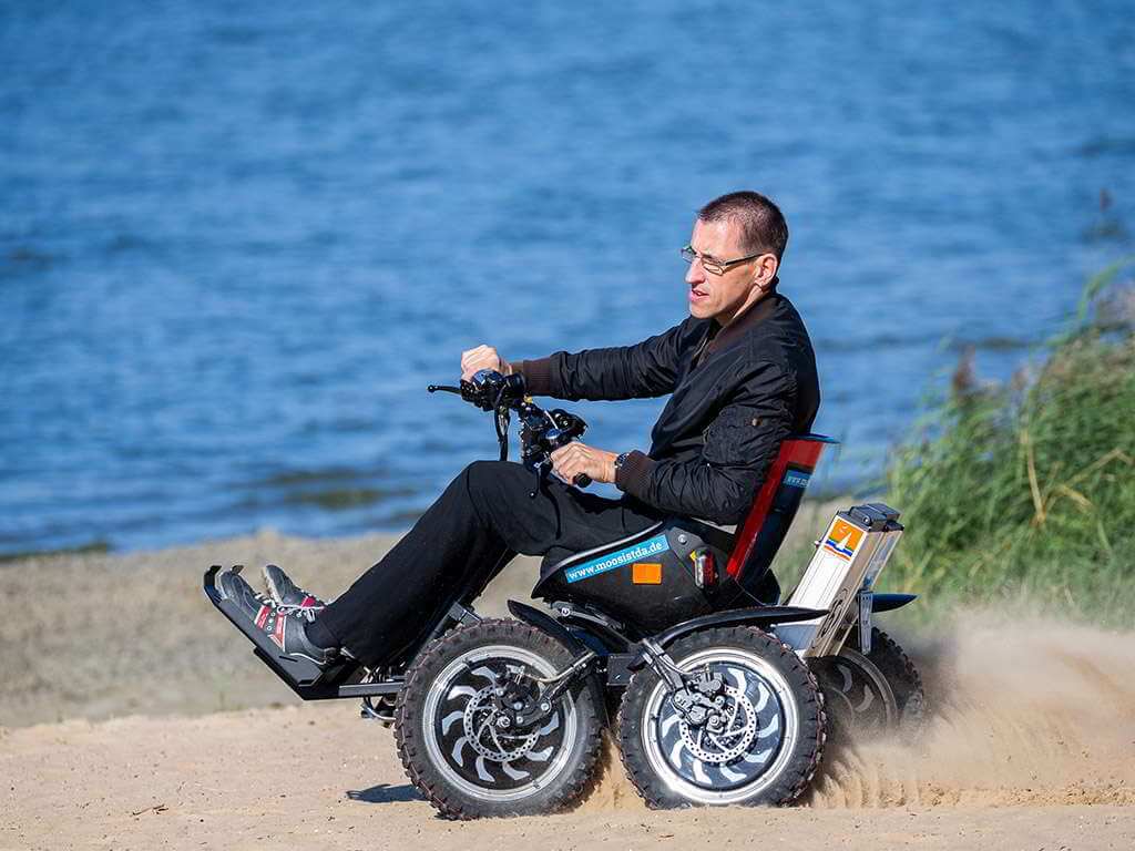 Ein Mann fährt mit dem motorisierten Rollstuhl "Zoom" über den Strand.